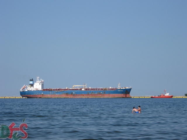 Widok z plaży na statek wpływający do portu